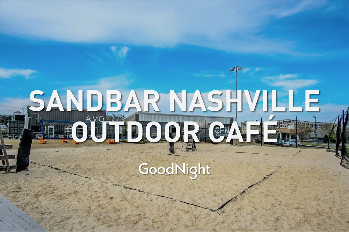 An outdoor scene with an inviting café, sand volleyball court, and open seating area, bustling with people socializing and enjoying food and drinks in a casual atmosphere.