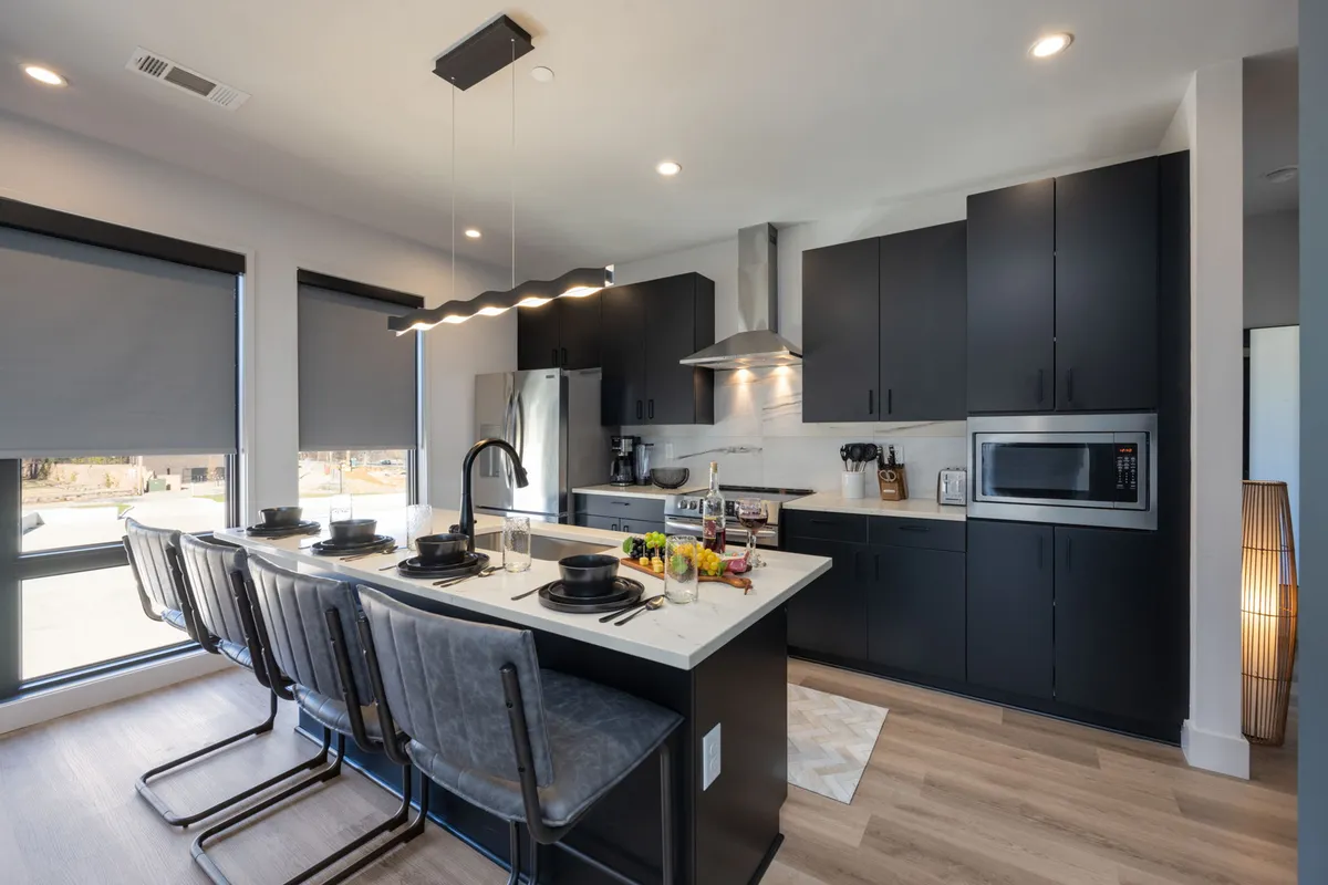 A contemporary kitchen with a sleek island, dining chairs, and elegant cabinetry, exuding a warm yet modern vibe. The setup encourages gathering for meals, cooking together, or hosting intimate dinner parties.
