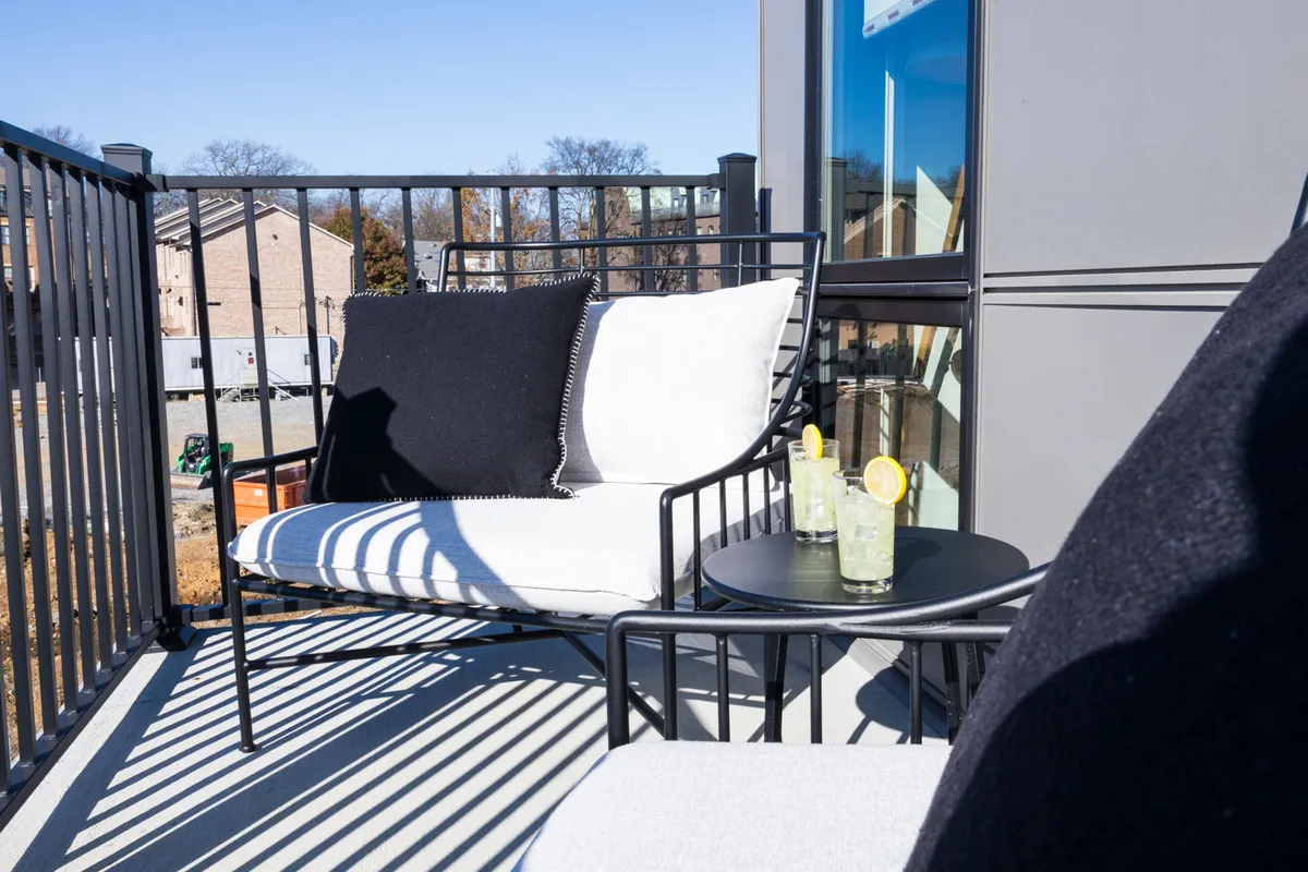 A cozy balcony scene featuring outdoor seating, drinks on the table, and a view over the balcony railing. The setting is inviting and suggests moments of relaxation, socializing, and enjoying the outdoors after a day of adventure.
