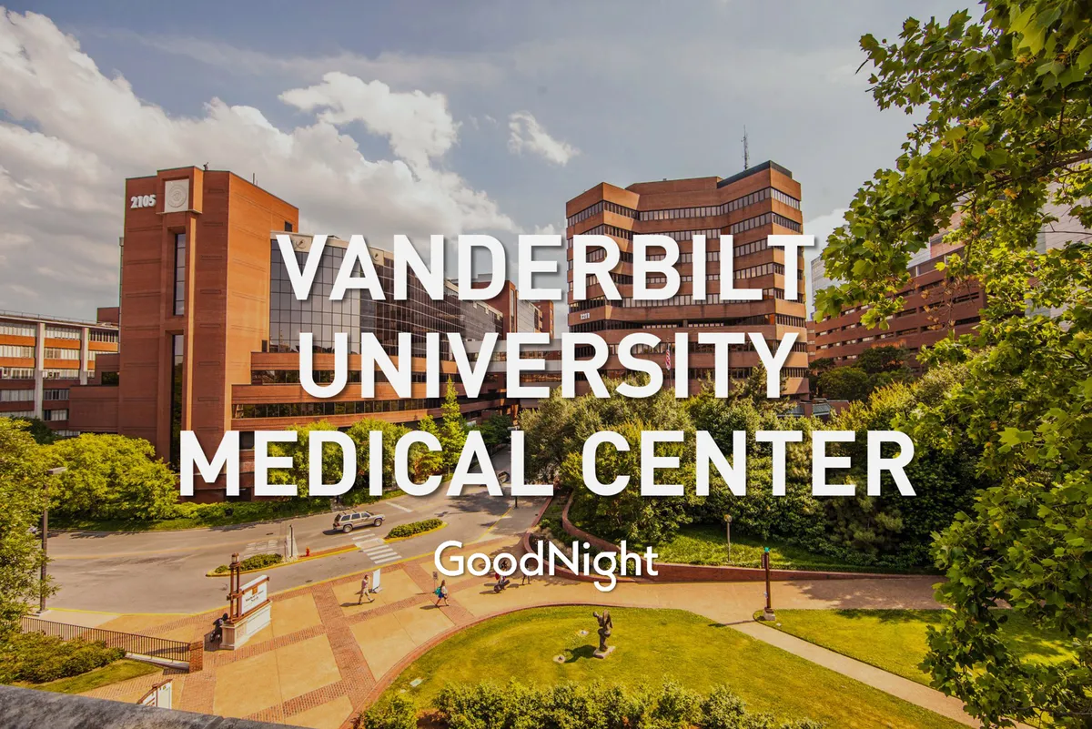 This image features the Vanderbilt University Medical Center building surrounded by lush greenery and pathways, capturing people engaging in activities like visiting patients, attending appointments, and enjoying the peaceful gardens. The setting evokes a sense of comfort and wellness, vital for medical travelers.